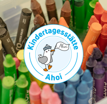 Eine kleine Kiste mit verschiedenen Farbstiften, ein Klebestift und eine kleine Schale mit kleinen Kugeln