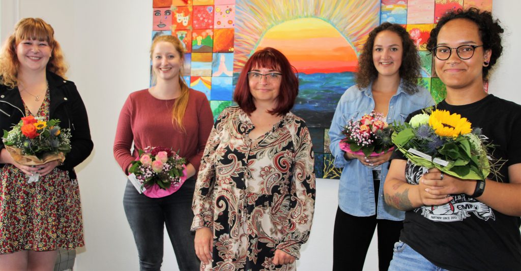 Man sieht jungen Frauen mit Blumensträuße und eine GPS Mitarbeiterinnen in der Mitte