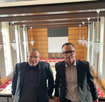 Ein Politiker und ein GPS Beschäftigter in einem großen Saal.