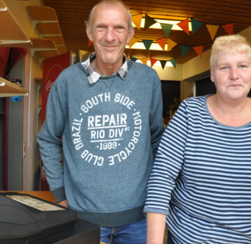 Zwei Mitarbeiter des GPS Kiosks. Ein Mann und eine Frau stehen vor der Kamera. Sie schauen freundlich.