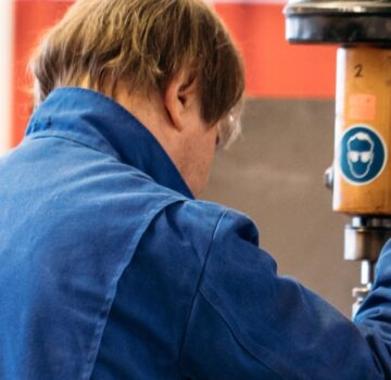 Ein Mann arbeitet in einer Werkstatt mit einem großen elektronischen Bohrer.