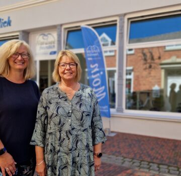 Draußen vor dem GPS Laden "Nordseefreundlich" sieht man zwei GPS Mitarbeiterinnen namens Bianca Rieken und Petra Mingo stehen und schauen in die Kamera.