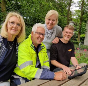 Zwei GPS Mitarbeiterinnen mit zwei Männern draußen im Garten am Tisch. Die zwei GPS Mitarbeiterinnen sind Sylvia Erhhardt Leiterin des "GPS Kindergarten Leuchtfeuer" und Britta Reusch-Sieberns von der "GPS Praxis für Logopädie".
