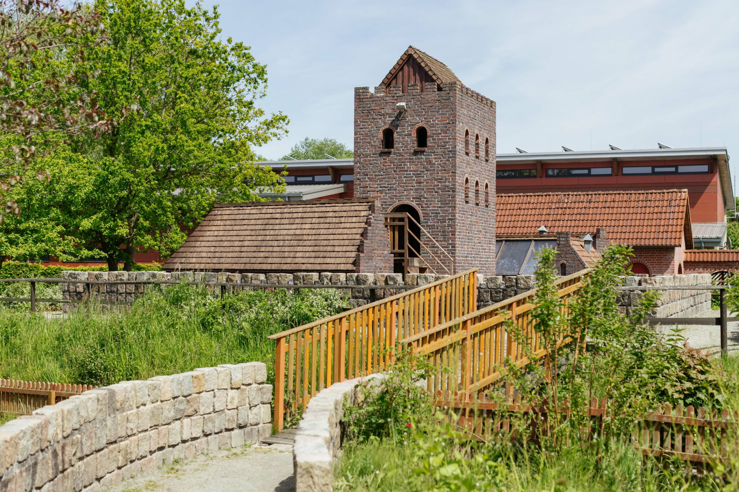 Draußen auf dem Gelände des Störtebeker Parks sieht man eine kleine Burg, eine Brücke und große Häuser.