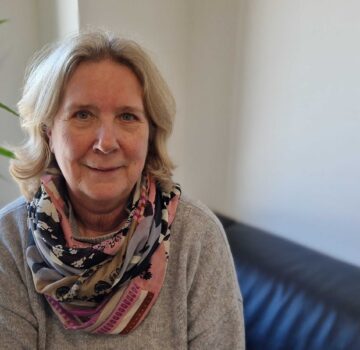Foto von Sabine Gastmann. Sie war die Leiterin vom Heilpädagogischen Wohnverbund von der GPS. Sie sitzt in einem Raum auf einer Couch.