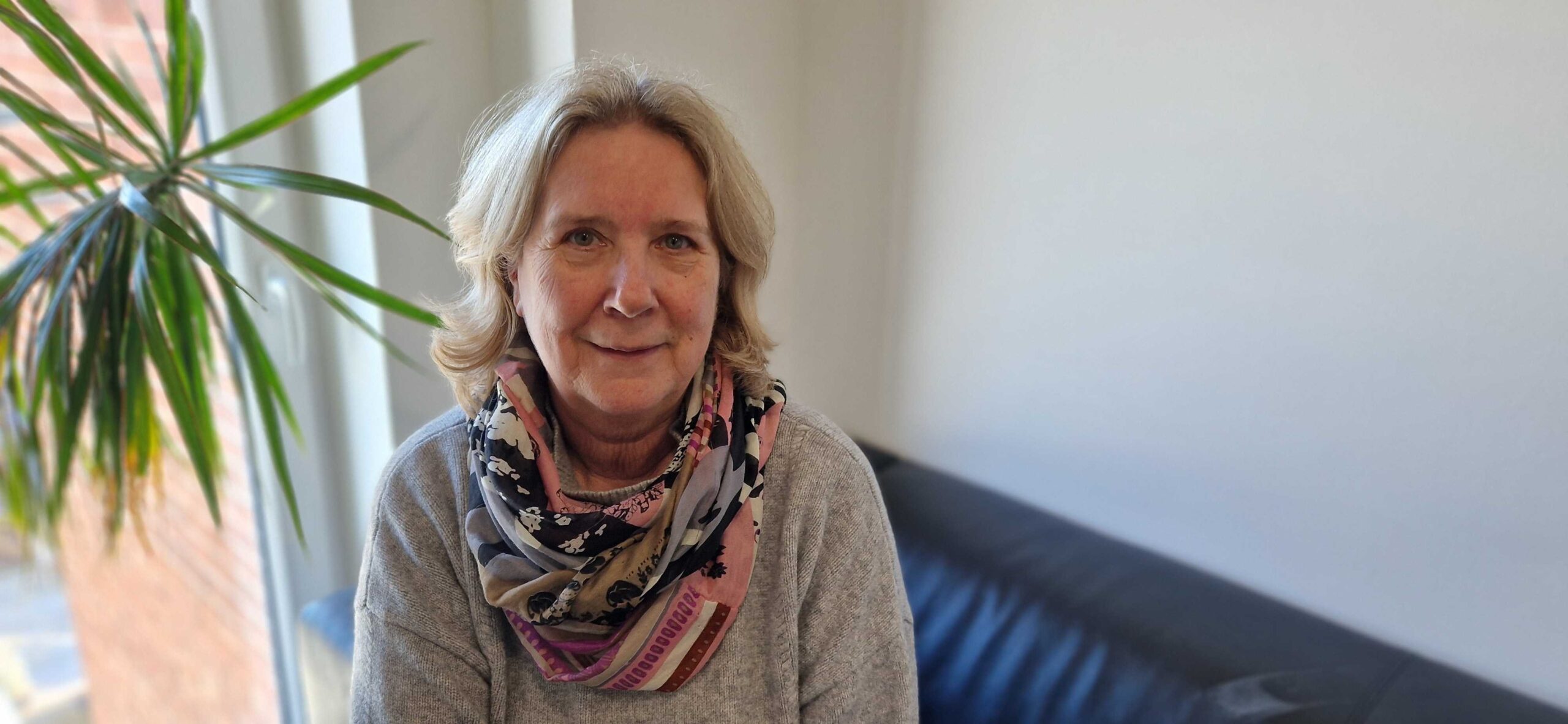Foto von Sabine Gastmann. Sie war die Leiterin vom Heilpädagogischen Wohnverbund von der GPS. Sie sitzt in einem Raum auf einer Couch.