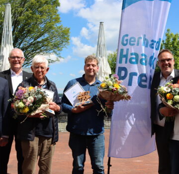 Ein Gruppenfoto mit den Gewinnern des Gerhard-Haack-Preises 2025 mit GPS Geschäftsführer Klaus Puschmann. Der Vorsitzende vom Paritätischen Wohlfahrtsverbandes Rainer Flinks und ein anderer älterer Mann vor der Kamera. Es scheint draußen die Sonne.