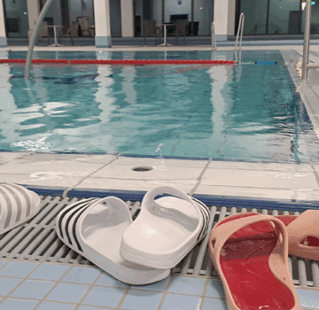 In einem Schwimmbad beim Schwimmbecken. Man sieht auch Sandalen.