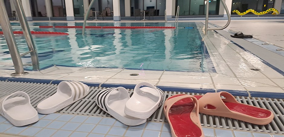 In einem Schwimmbad beim Schwimmbecken. Man sieht auch Sandalen.