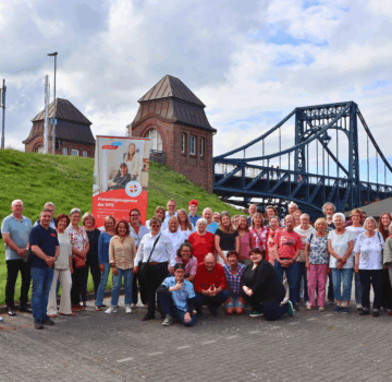 Gruppenfoto Ehrenamtliche beim Südstrand in Wilhelmshaven. Im Hintergrund sieht man die Kaiser-Wilhelm-Brücke.