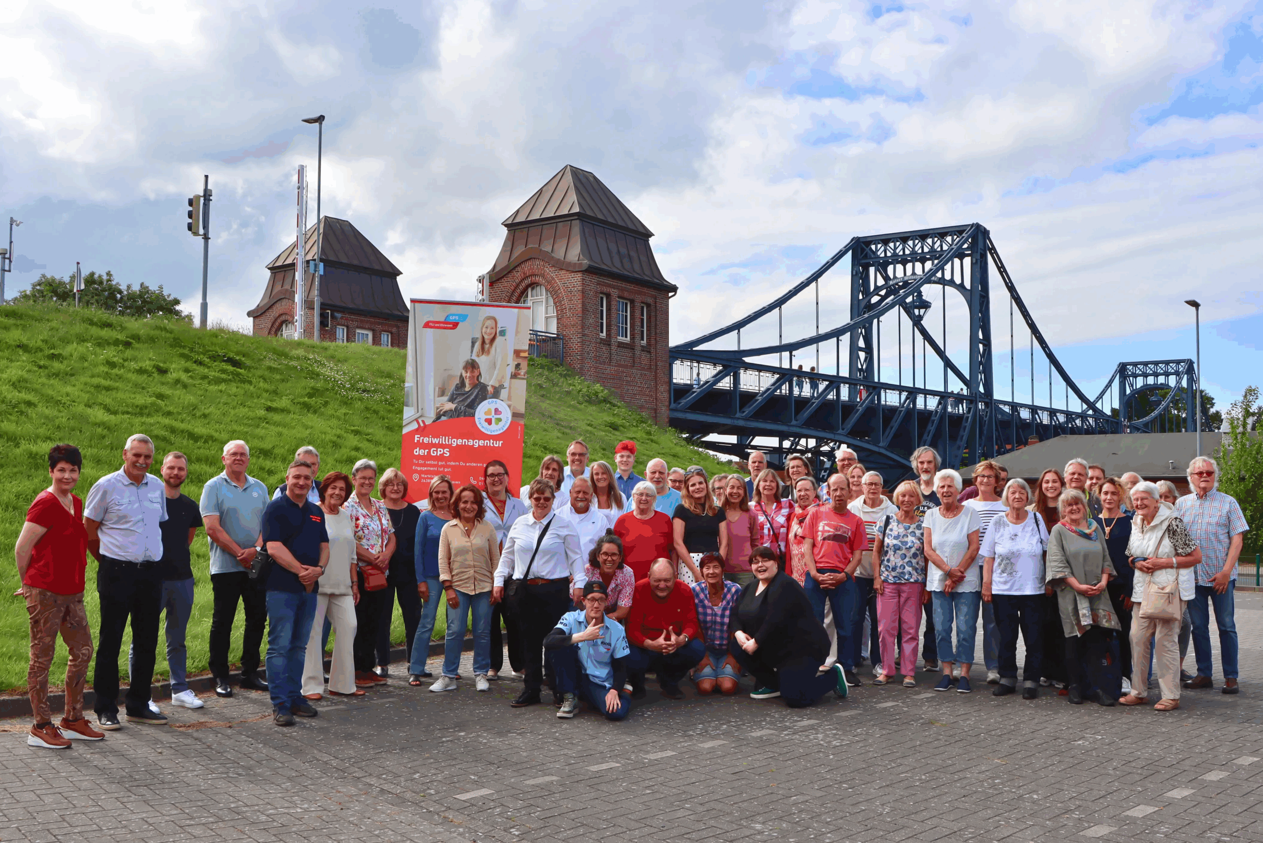 Gruppenfoto Ehrenamtliche beim Südstrand in Wilhelmshaven. Im Hintergrund sieht man die Kaiser-Wilhelm-Brücke.