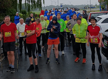 Ein Gruppenfoto mit vielen Menschen vor der Kamera. Sie haben alle Sportsachen an. Draußen regnet es.