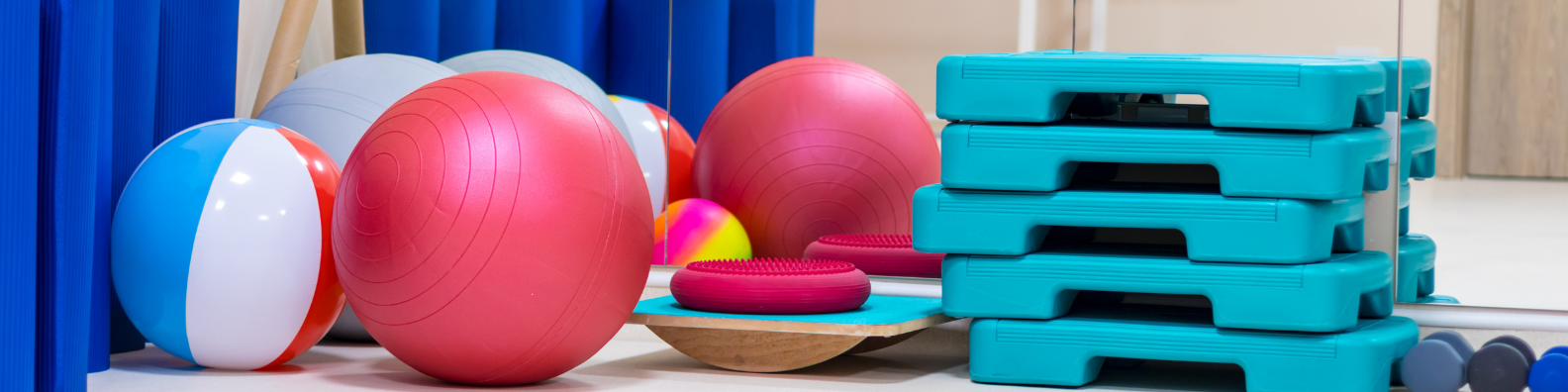 Viele Sportgeräte wie zum Beispiel viele Gymnastikbälle, Hanteln und Stepper.