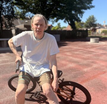 Ein Mann mit einem BMX Fahrrad auf einem Sportplatz