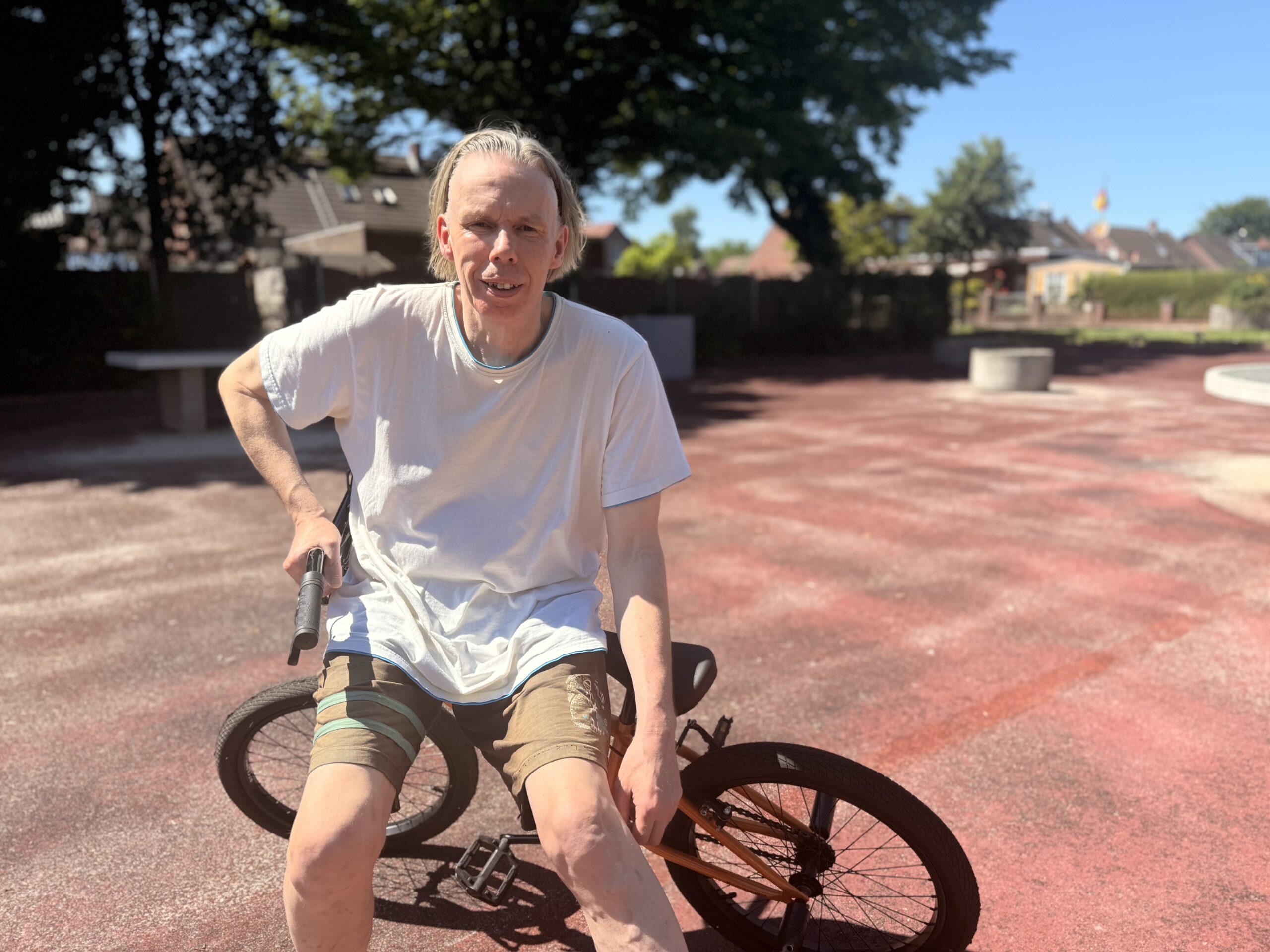 Ein Mann mit einem BMX Fahrrad auf einem Sportplatz