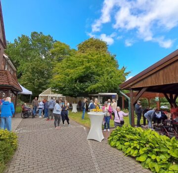 Draußen bei schönen Wetter auf einem Innenhof bei einer Veranstaltung. Man sieht viele Menschen auf dem Bild.