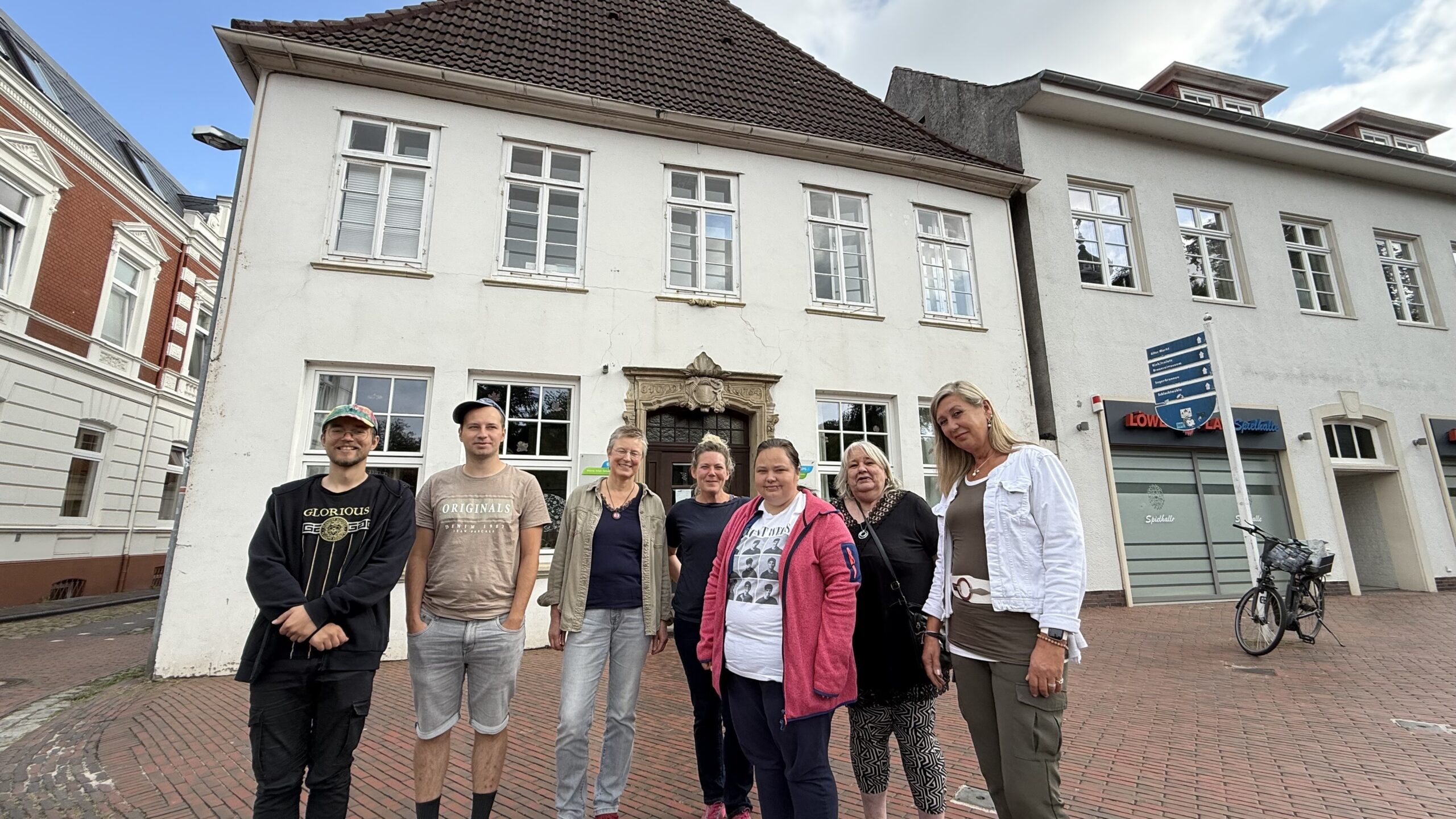 Ein Gruppenfoto mit Männer und Frauen draußen vor der Tagesstätte Schlosskäserei in Jever.