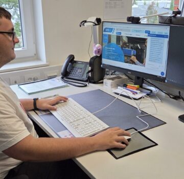 Ein junger Praktikant in der Abteilung "Kommunikation & Marketing" bei der GPS. Er sitzt an einem Schreibtisch und macht seine Aufgaben an einem Computer.