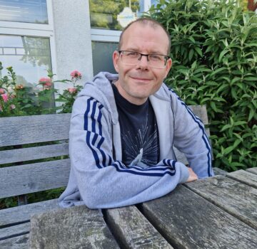 Ein GPS Beschäftigter namens Massimo Marongiu. Er sitzt draußen im Garten der GPS Werkstatt "ARTEC Roffhausen".