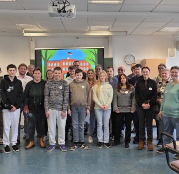 Ein Gruppenfoto mit jungen und älteren Leuten in einem großen Raum zu der Veranstaltung "Tag der Begegnung"