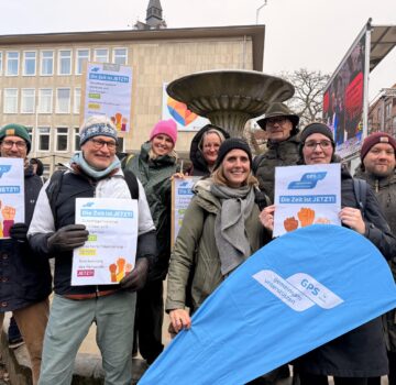 GPS Mitarbeiter und Mitarbeiterinnen bei einer Demonstration in einer Stadt draußen. Sie halten Plakate in der Hand.