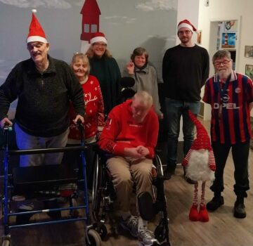 Ein Gruppenfoto Weihnachtsverlosung in der WG Leuchtturm. Man sieht fünf GPS Beschäftigte und zwei GPS Mitarbeiter auf dem Bild.