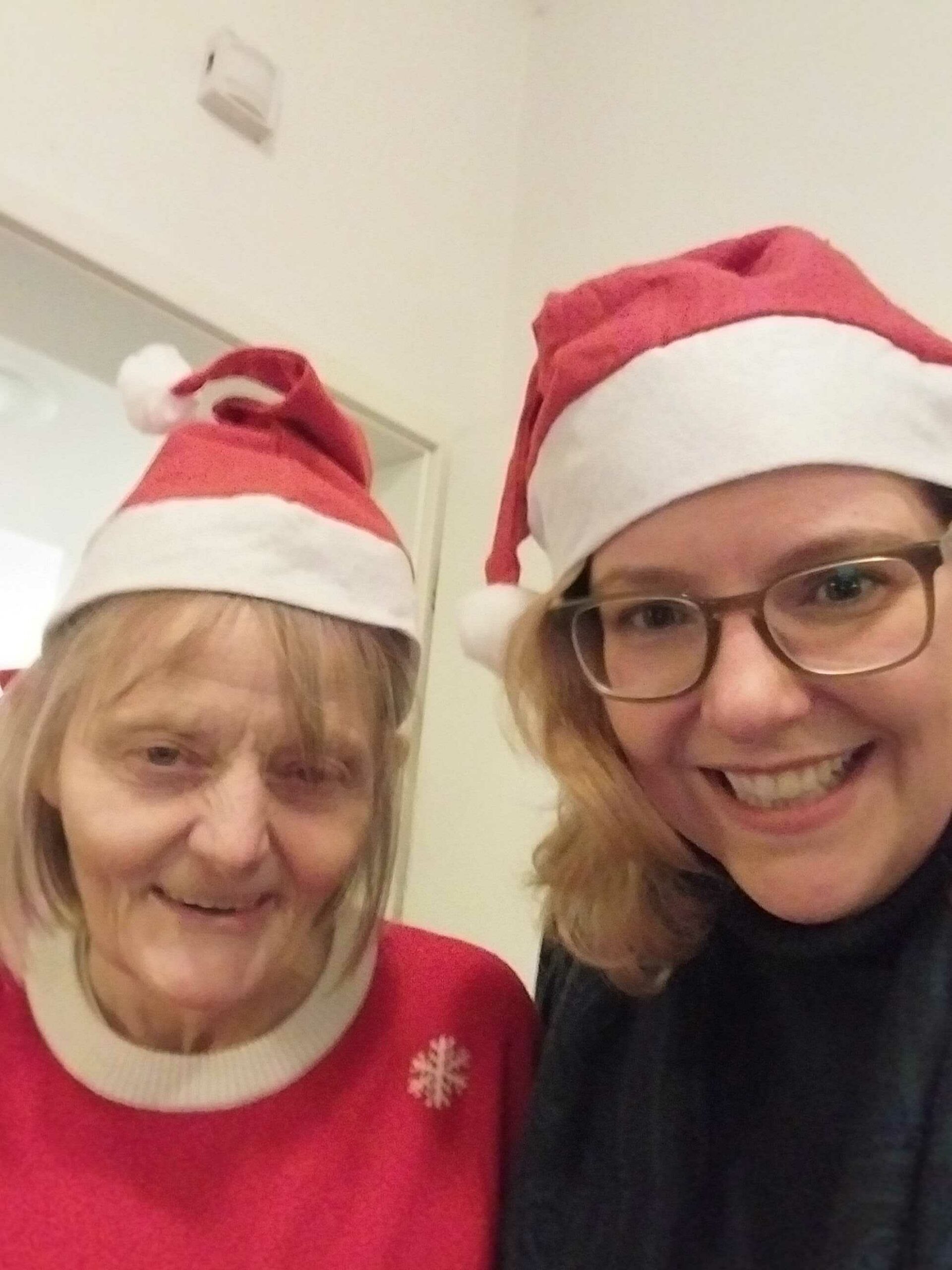 Ein Gruppenfoto GPS Weihnachtsverlosung in der WG Leuchtturm mit einer GPS Mitarbeitern Nicole Stappenbeck (Abteilung Fundraising) und eine ältere GPS Beschäftigte. Beide habe eine Weihnachtsmütze auf.